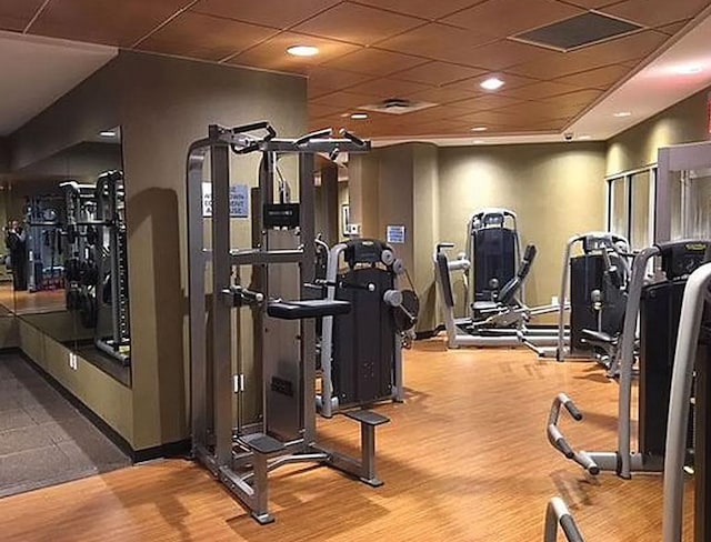workout area with wood finished floors and a drop ceiling