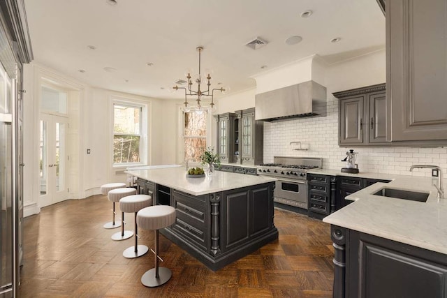 243 E 17th St, New York City, NY 10003 - kitchen featuring a sink, high end stainless steel range, wall chimney exhaust hood, a breakfast bar, and decorative backsplash