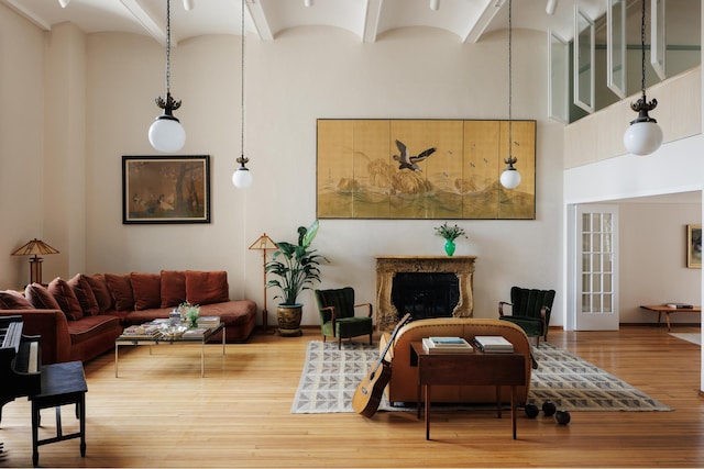 living room featuring a high ceiling, a fireplace, and wood finished floors