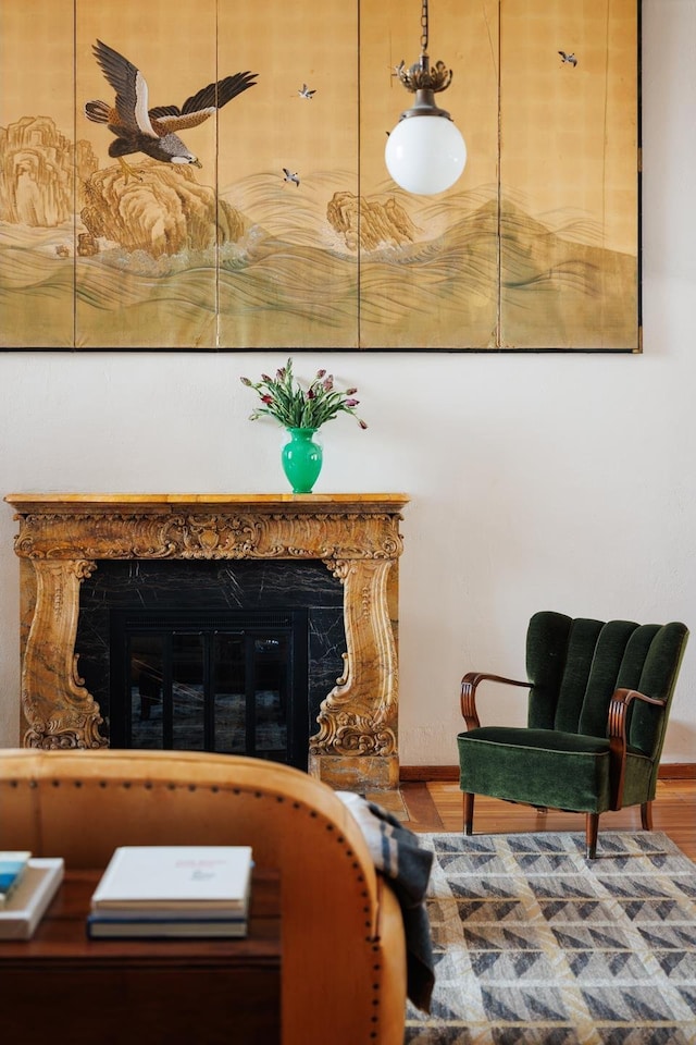 sitting room with a premium fireplace, baseboards, and wood finished floors
