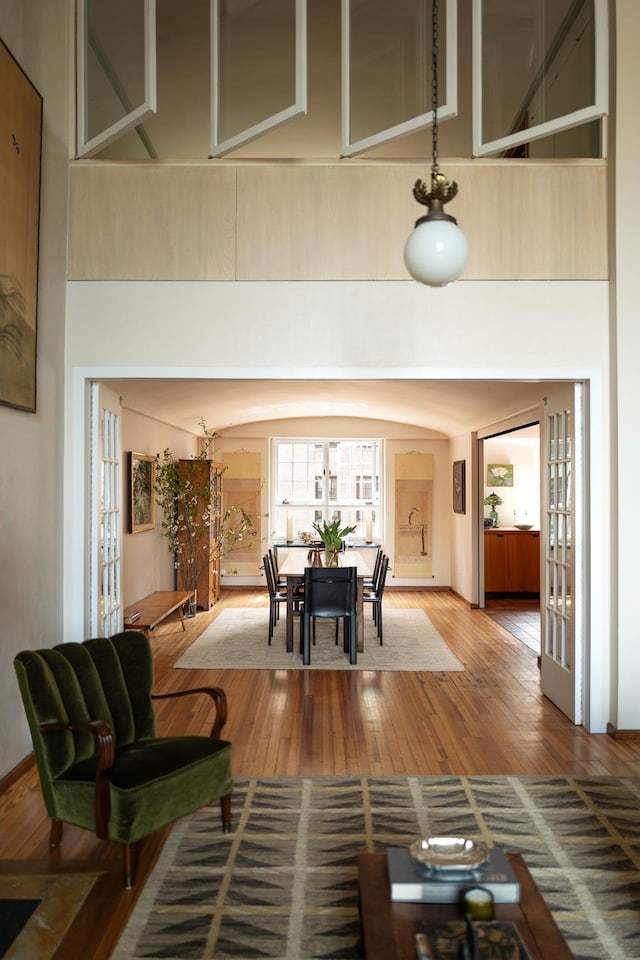 living area with hardwood / wood-style floors, french doors, and arched walkways