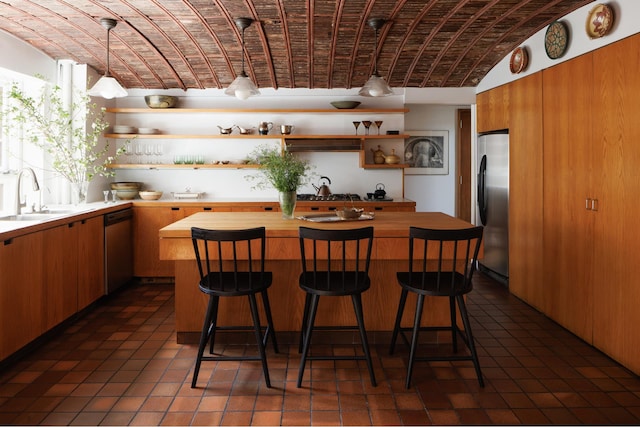 kitchen with open shelves, appliances with stainless steel finishes, a sink, wooden counters, and brick ceiling