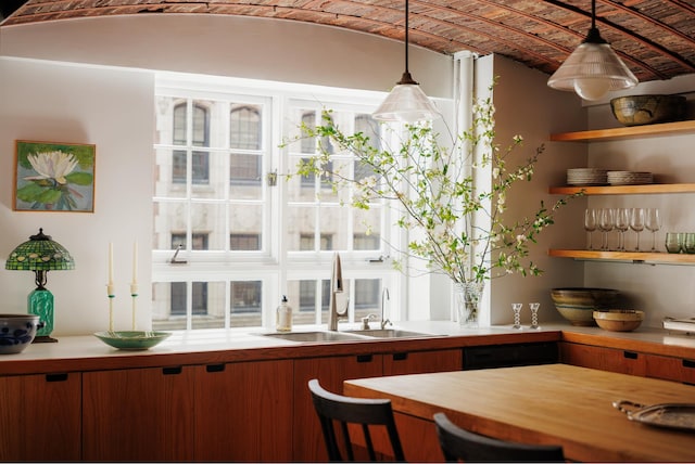 bar with a sink, pendant lighting, and black dishwasher