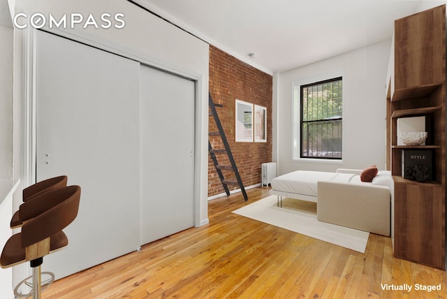 331 E 92nd St Unit 1A, New York City, NY 10128 - bedroom featuring radiator heating unit, brick wall, light wood finished floors, and a closet