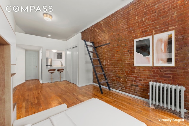331 E 92nd St Unit 1A, New York City, NY 10128 - living area featuring radiator, hardwood / wood-style flooring, and brick wall