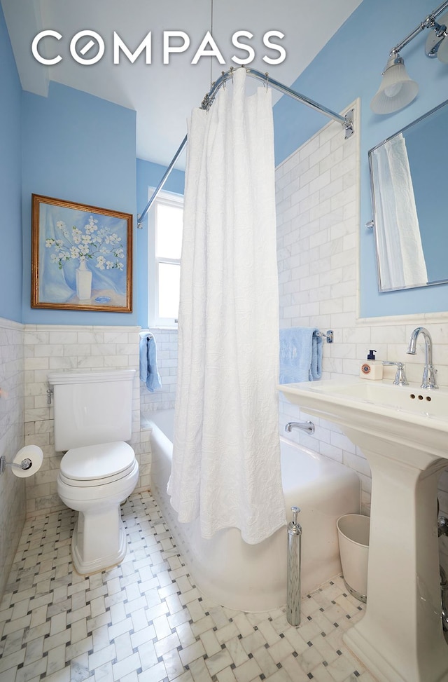 162 E 80th St Unit 5B, New York City, NY 10075 - bathroom with tile walls, shower / bath combo with shower curtain, and a wainscoted wall