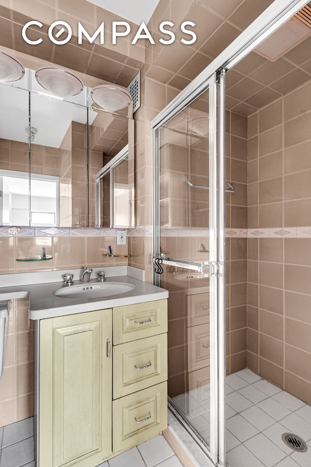 345 E 52nd St Unit 10Cd, New York City, NY 10022 - bathroom with a stall shower, vanity, tile patterned floors, and tile walls