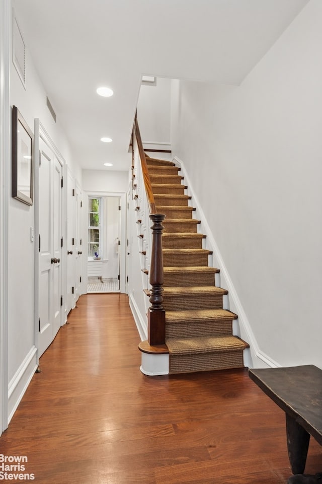 staircase with wood finished floors, recessed lighting, and baseboards