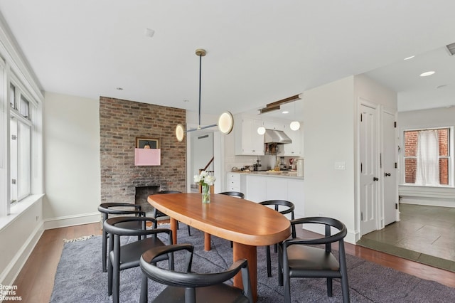 dining room with a brick fireplace, dark wood-style floors, baseboards, and recessed lighting