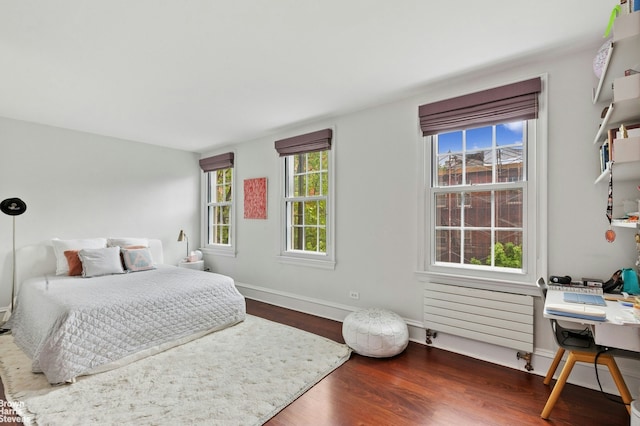 bedroom featuring wood finished floors, baseboards, and radiator heating unit