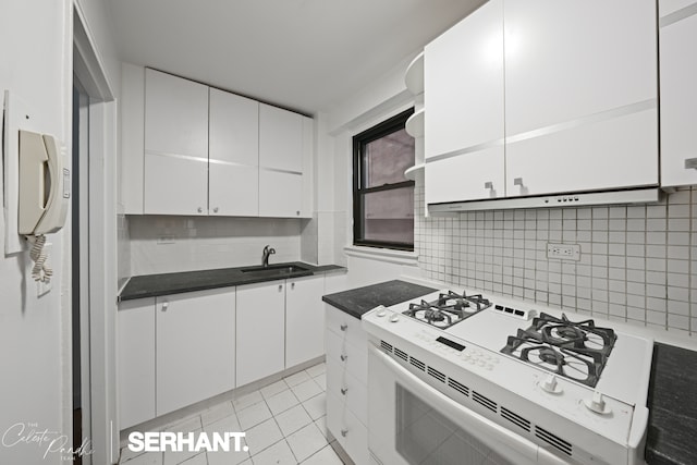 301 E 63rd St Unit 3B, New York City, NY 10065 - kitchen with white gas stove, a sink, backsplash, white cabinetry, and dark countertops