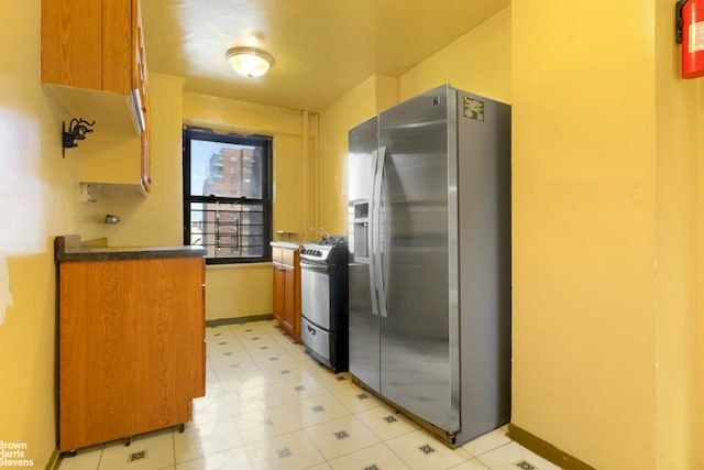 210 E Broadway Unit H1401, New York City, NY 10002 - kitchen with stainless steel appliances, brown cabinets, dark countertops, and baseboards