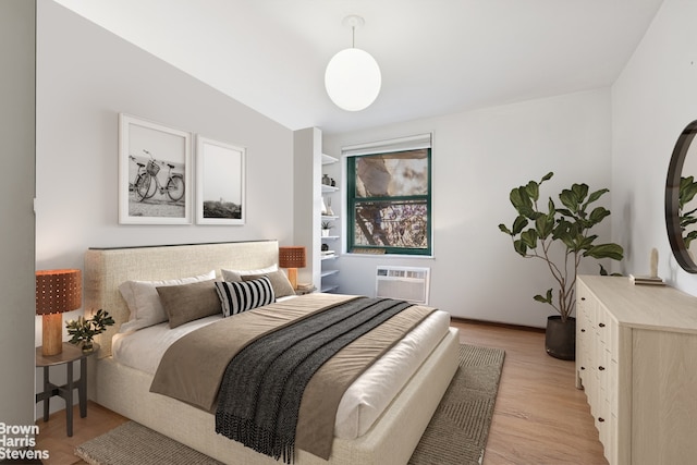 bedroom featuring a wall unit AC and light wood finished floors