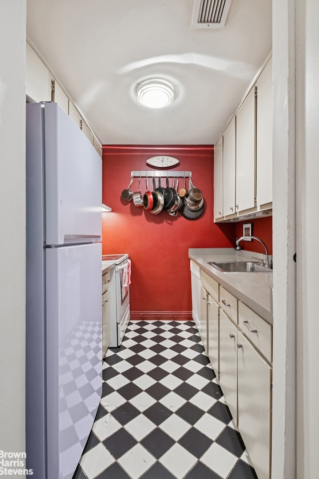 kitchen featuring white appliances, light floors, a sink, light countertops, and white cabinetry