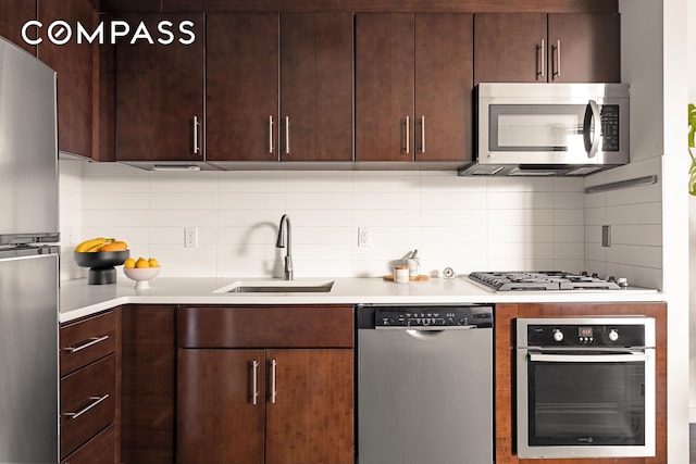 kitchen with stainless steel appliances, a sink, tasteful backsplash, light countertops, and dark brown cabinets