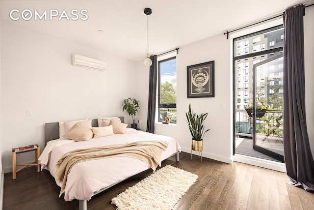 bedroom featuring access to exterior, a wall mounted air conditioner, multiple windows, and wood finished floors