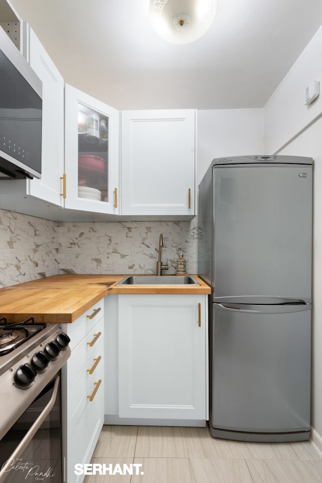 430 E 77th St Unit 4B, New York City, NY 10075 - kitchen featuring stainless steel appliances, a sink, wooden counters, and white cabinetry