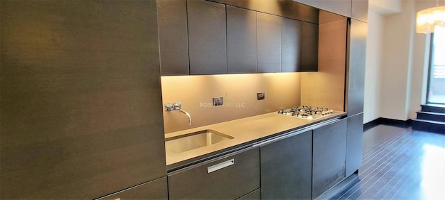 kitchen with a sink, stainless steel gas stovetop, modern cabinets, and baseboards