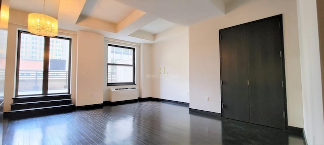 unfurnished room with a chandelier, dark wood-style flooring, and baseboards