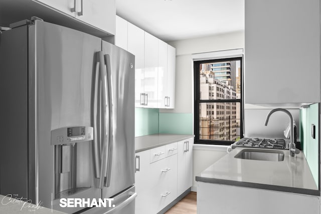 kitchen with stainless steel fridge, plenty of natural light, a sink, and white cabinetry