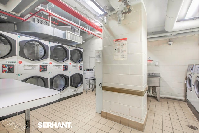 community laundry room featuring stacked washer / drying machine, separate washer and dryer, and light tile patterned floors