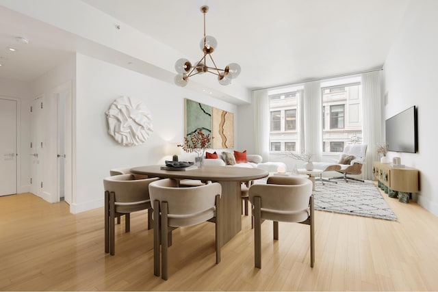 dining area featuring a chandelier, light wood-style flooring, and baseboards