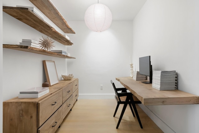 home office with light wood-style flooring and baseboards