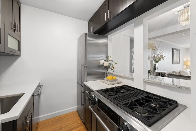 330 E 70th St Unit 2-H, New York City, NY 10021 - kitchen with stainless steel appliances, light wood finished floors, baseboards, a sink, and light stone counters