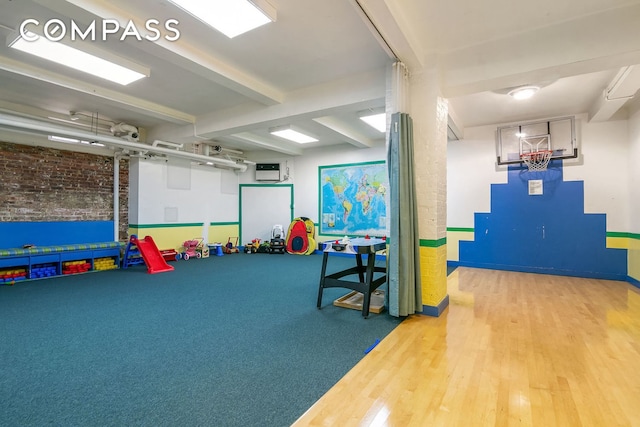 250 W 94th St Unit 11A, New York City, NY 10025 - playroom with wood finished floors, beamed ceiling, brick wall, and baseboards