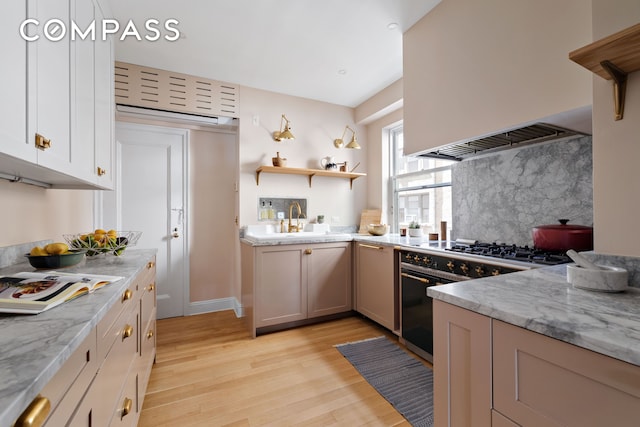 250 W 94th St Unit 11A, New York City, NY 10025 - kitchen with light wood finished floors, high end black range oven, decorative backsplash, custom exhaust hood, and a sink