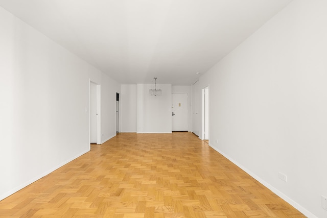 empty room featuring a chandelier and baseboards