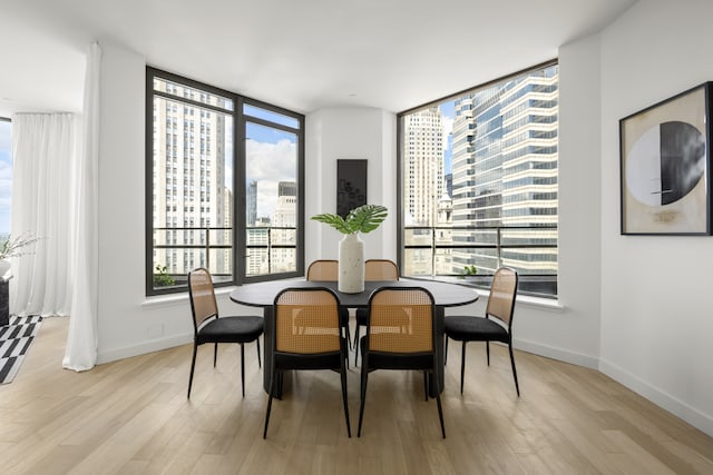 75 Wall St Unit Phl3, New York City, NY 10005 - dining room with a city view, light wood-style floors, expansive windows, and baseboards