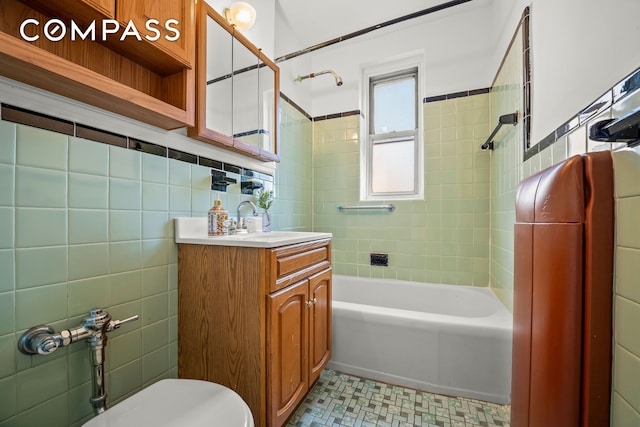 bathroom with tile walls,  shower combination, vanity, toilet, and tile patterned floors