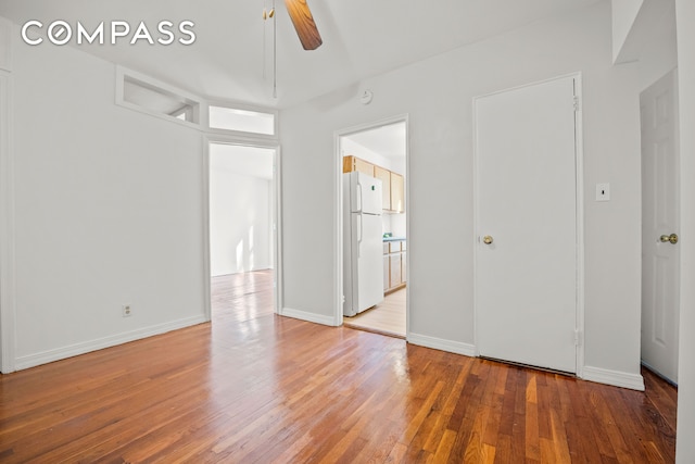 empty room with light wood-style floors, a ceiling fan, and baseboards