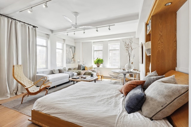 bedroom with track lighting and wood finished floors