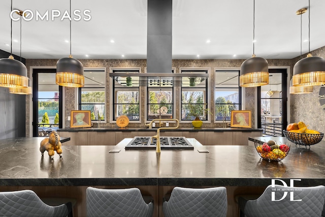 kitchen with stainless steel gas cooktop, dark countertops, a breakfast bar, hanging light fixtures, and modern cabinets