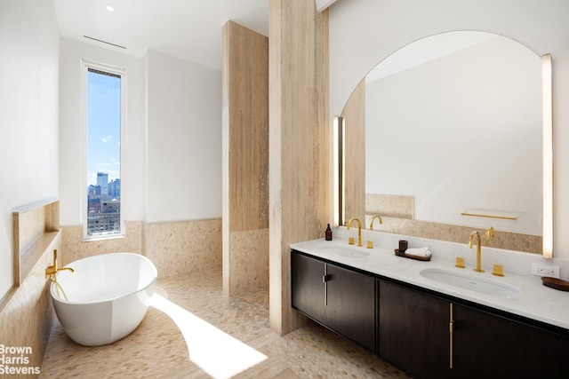 bathroom featuring healthy amount of natural light, a freestanding bath, double vanity, and tile patterned floors