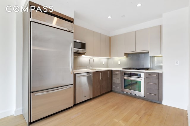 2300 Frederick Douglass Blvd Unit 8D, New York City, NY 10027 - kitchen with stainless steel appliances, light wood-style floors, light countertops, decorative backsplash, and exhaust hood