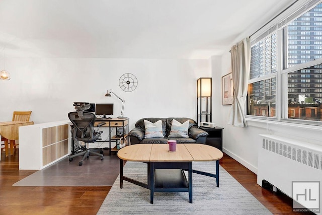 living area featuring radiator, an office area, wood finished floors, and baseboards