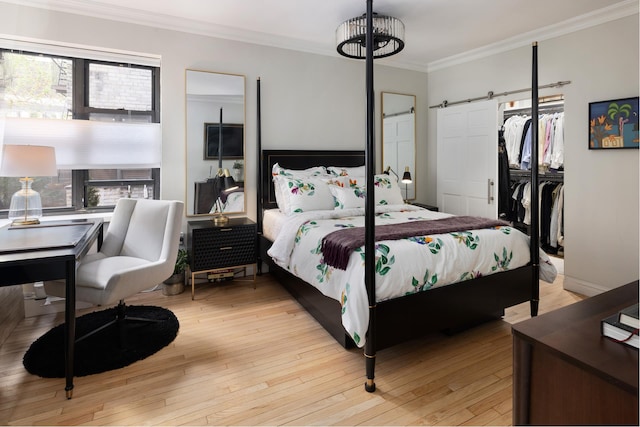 bedroom featuring a barn door, multiple windows, crown molding, light wood-style flooring, and a closet