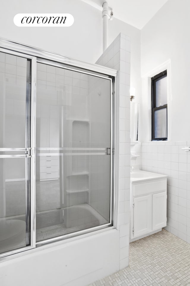 140 W 69th St Unit 124A, New York City, NY 10023 - bathroom featuring tile walls, vanity, tile patterned flooring, and enclosed tub / shower combo