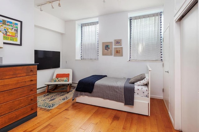 88 Meserole Ave Unit 1B, New York City, NY 11222 - bedroom with light wood-type flooring, baseboards, track lighting, and a baseboard heating unit