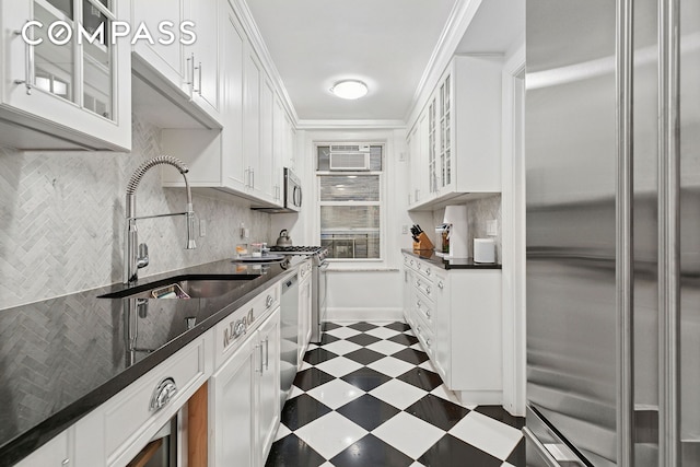 kitchen with appliances with stainless steel finishes, a sink, dark floors, white cabinets, and glass insert cabinets