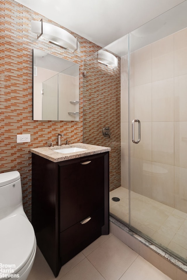 bathroom featuring tile patterned flooring, tile walls, toilet, a shower stall, and vanity