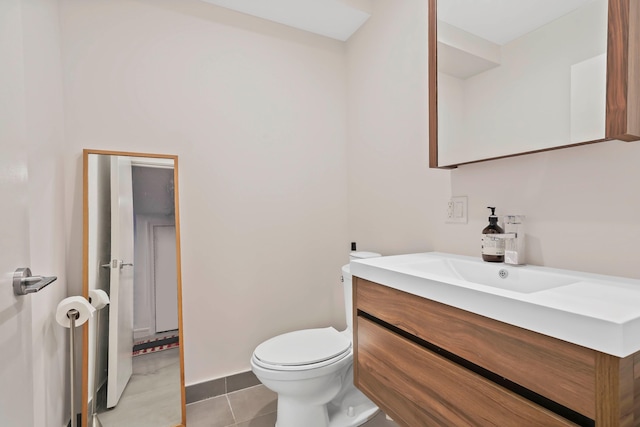 bathroom with toilet, vanity, and tile patterned floors