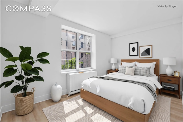bedroom featuring radiator, wood finished floors, and baseboards
