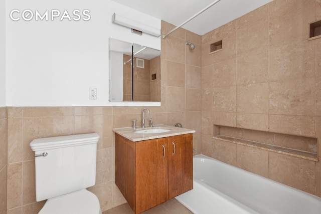 full bath with tile walls, toilet, shower / washtub combination, and vanity