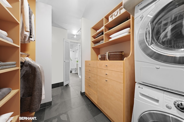 270 W 17th St Unit 12Bc, New York City, NY 10011 - laundry area with stacked washer / dryer and dark tile patterned floors