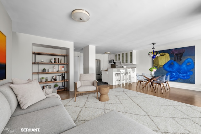 270 W 17th St Unit 12Bc, New York City, NY 10011 - living room featuring wood finished floors, a chandelier, and baseboards