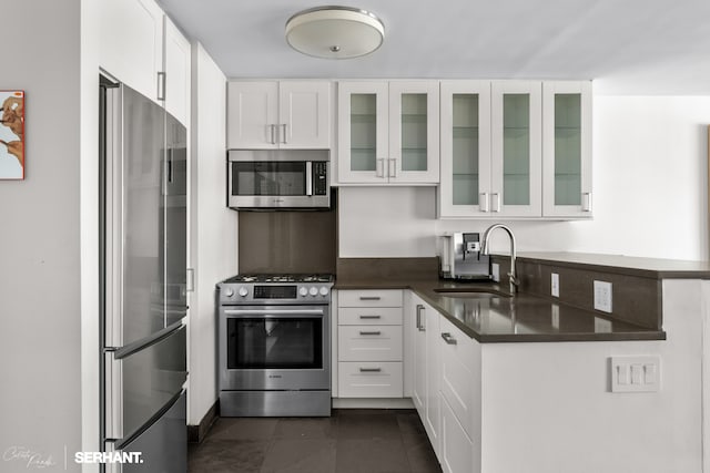270 W 17th St Unit 12Bc, New York City, NY 10011 - kitchen featuring stainless steel appliances, a sink, dark countertops, white cabinets, and glass insert cabinets